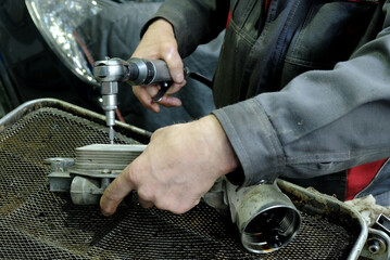 Maintenance and repair of cars in the service center. Close-up of the hands of a mechanic who replaces the gaskets of the internal combustion engine heat exchanger.