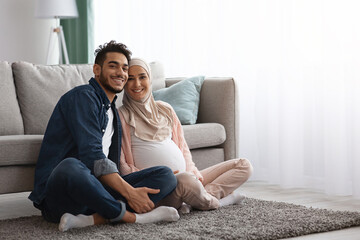 Obraz premium Happy Pregnant Muslim Couple Relaxing At Home Together, Sitting On Floor