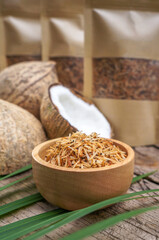 Homemade roasted coconut and in a wooden bowl and in a paper bags placed on the table.