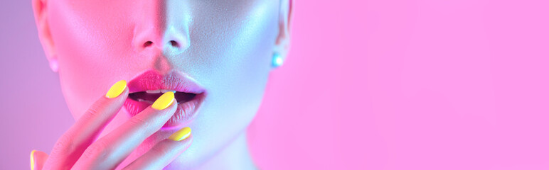 Fille modèle haute couture dans des lumières UV lumineuses colorées posant en studio, portrait de belle femme avec maquillage tendance et manucure. Design artistique, maquillage coloré. Sur fond coloré.