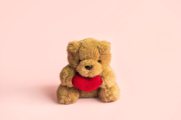 Cute teddy bear with red heart on color background and copy space, Valentine's Day concept