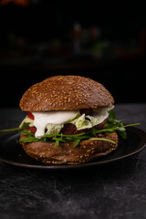 Fresh burger with vegan meat and vegetables, sprinkled with sesame seeds
