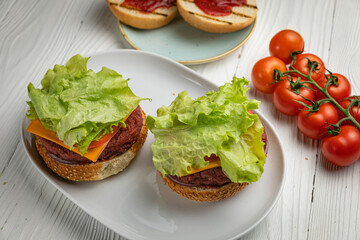 Sandwiches with cutlet, salad, tomato. On a white wooden table
