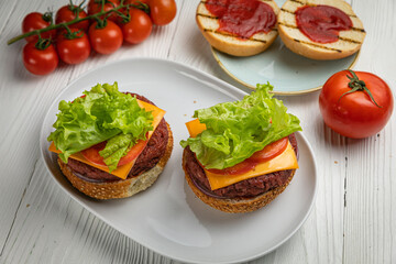 Sandwiches with cutlet, salad, tomato. On a white wooden table
