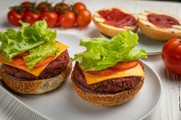Sandwiches with cutlet, salad, tomato. On a white wooden table
