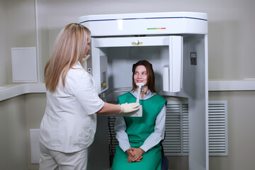 X-ray equipment in a dental clinic. The dentist prepares the patient for dental x-rays. Modern dentistry. The concept of treatment and prevention of dental diseases. The patient smiles.