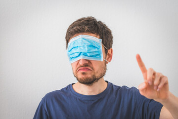 Young angry man is wearing face mask over the eyes and gesturing angry. Conspiracy theory concept.