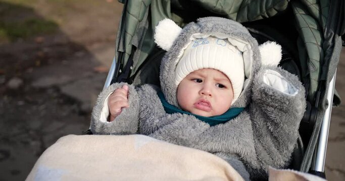 baby boy rides in a stroller in winter in sunny weather. little boy in carriage