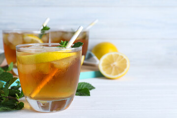 Delicious iced tea in glass on white wooden table, space for text