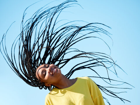portrait of a young black woman with long hair, african braids or dreadlocks, isolated outdoors