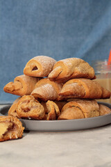 Homemade pastry. The rugelach with apple jam and condensed milk in a gray plate on a table. Traditional Jewish holiday cookie, Bagels, Croissants, Still life with cookies and blue textile background