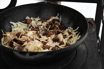 Meat and onion in cauldron on oven. Outdoor cooking.