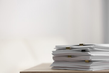 Stack of blank paper with binder clips on wooden table. Space for text