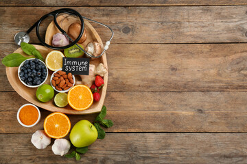 Card with phrase Immune System, stethoscope and fresh products on wooden table, flat lay. Space for text