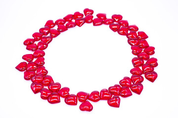 Bright red hearts are shiny, glass lie in the form of a round frame on a white background. Concept...