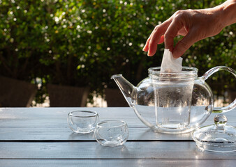 Fototapeta na wymiar older people put tea bag into glass kettle to make hot afternoon tea in garden