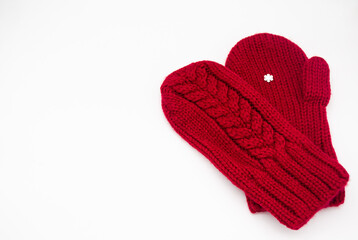 A knitted red mitten with white snowflake in the shape of a heart on a white background, isolated. Concept of Christmas, winter, love, care and Valentines day. Copy space
