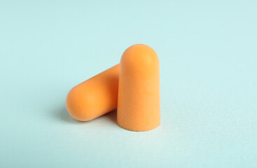 Pair of orange ear plugs on turquoise background