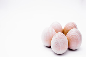 Five hand-made unpainted wooden eggs on a white background