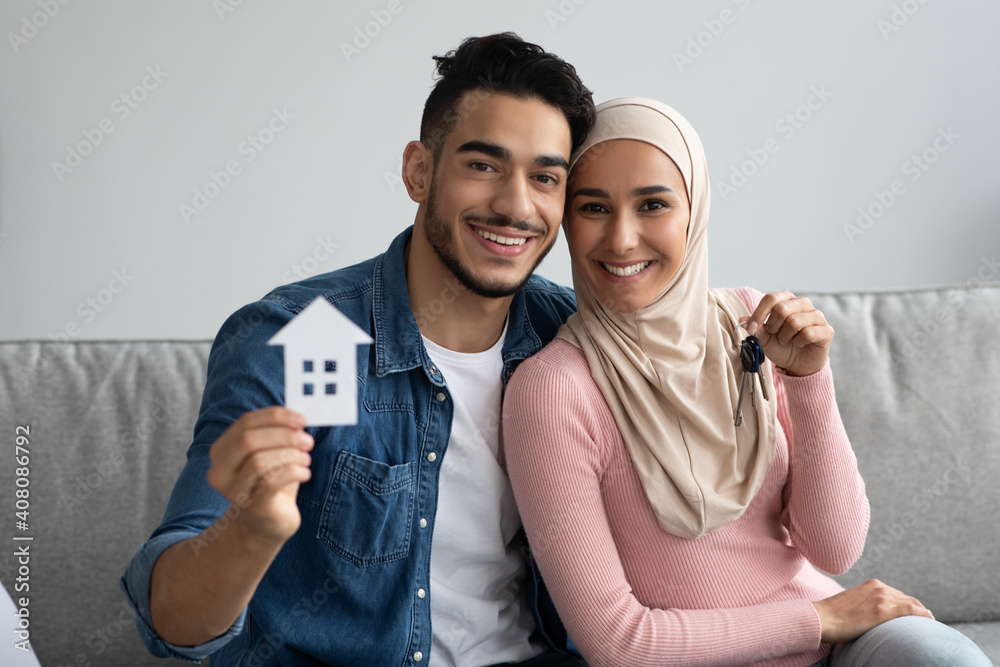 Wall mural young smiling muslim couple holding their new house keys