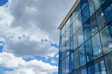 Fototapeta na wymiar Modern glass building architecture on blue sky background, copy space. Windowed corner of office building