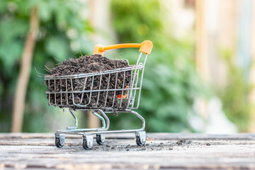 Manure on mini shopping cart with natural light background (Business and finance concept)
