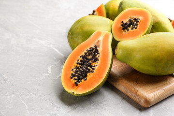 Fresh ripe papaya fruits on light grey table. Space for text