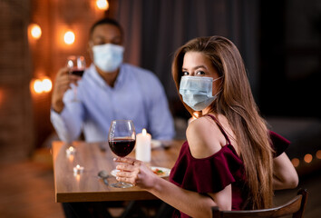 Pandemic Date. Young Interracial Couple In Medical Masks Having Dinner In Restaurant