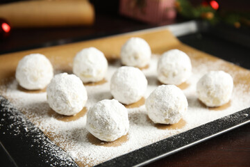 Fototapeta na wymiar Christmas snowball cookies on baking tray, closeup