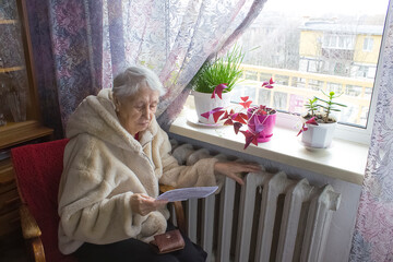 Woman holding cash in front of heating radiator. Payment for heating in winter. Selective focus.