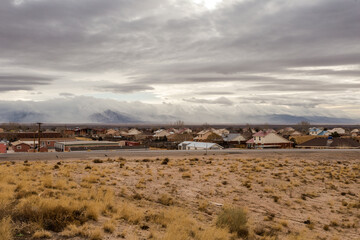 Thick fog rolling over mountains in the distance behind a small town on overcast day in rural New Mexico