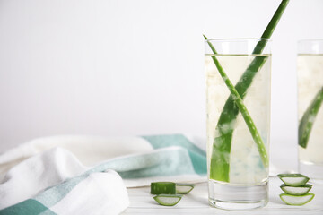 Fresh aloe drink with leaves in glasses on white wooden table. Space for text
