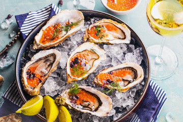 Oysters platter with lemon caviar and ice served on a Blue marine table.