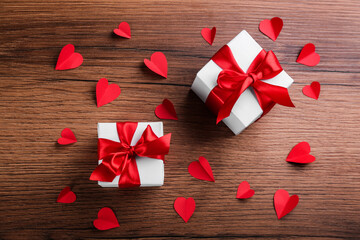 Beautiful gift boxes and paper hearts on wooden table, flat lay. Valentine's Day celebration