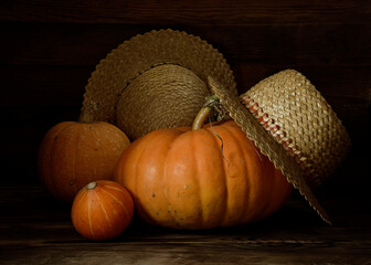 Pumpkins and straw hats on a wooden table.