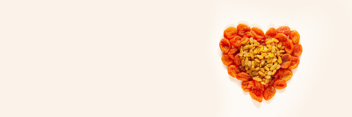 Dried apricots and raisins are laid out in the form of two hearts on a beige background. Healthy eating. Food for heart health. Sweets for pregnant women. Vegan food. View from above. Valentine's Day.