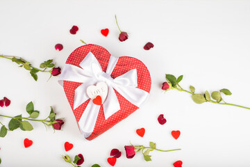 Gift box shape of a heart with bow isolated on white background with red roses and decorative heart. Wooden decorative hearts.