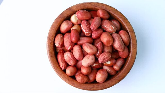 close up peanuts in wood bowl on white.