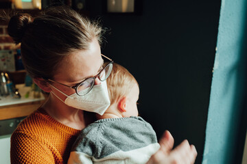 Frau mit Maske und Kind. Junge Frau mit ihrem kranken Kind während der Corona Pandemie