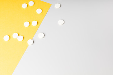 Pills on white and yellow backgrounds