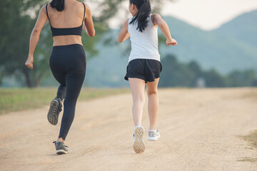 two female runners jogging outdoors in forest in autumn nature..running sporty mother and daughter....