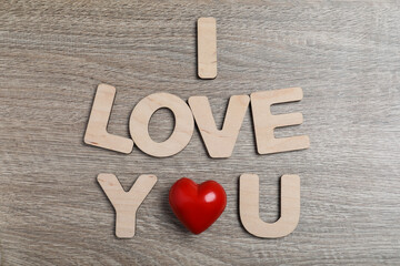 Phrase I Love You made of decorative heart and letters on wooden background, flat lay