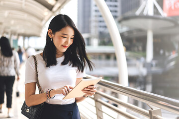 Young adult business working asian woman using digital tablet for online application on day.