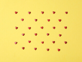 Bright heart shaped sprinkles on yellow background, flat lay