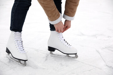 Woman lacing figure skate on ice rink, closeup