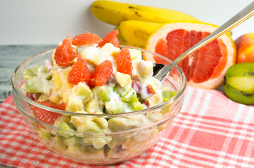Fruit salad dressed with yogurt. Fresh sliced fruits are healthy food.