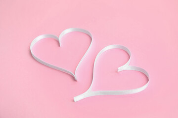 Hearts made of white ribbon on pink background. Valentine's day celebration