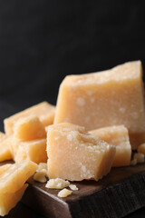 Pieces of delicious parmesan cheese on wooden board, closeup