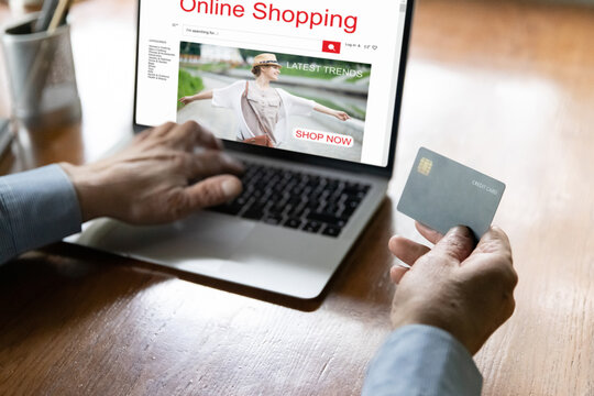 Close up mature man making secure internet payment, holding plastic credit card, typing, entering information, using laptop, elderly customer browsing online shopping website, computer screen, buying
