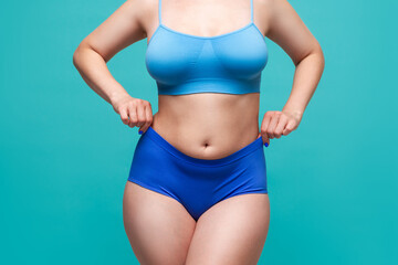 Fototapeta na wymiar Plus size model in blue underwear on turquoise background